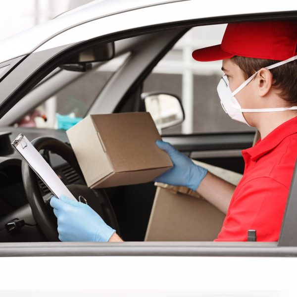 Many parcels for delivery during quarantine. Deliveryman checks address of package